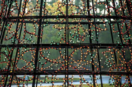 Colorful holiday lights shaped like stars are arranged in a decorative pattern on a structure.