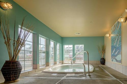 A bright indoor spa area with a hot tub, large windows, and decorative plants against a teal wall.