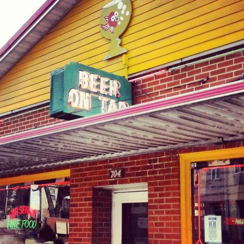 A colorful building with a sign that reads "Beer on Tap" above a brick facade, featuring a whimsical fish design.