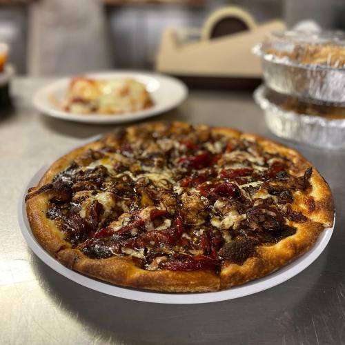 A freshly baked pizza topped with melted cheese, caramelized onions, and red peppers on a white plate.
