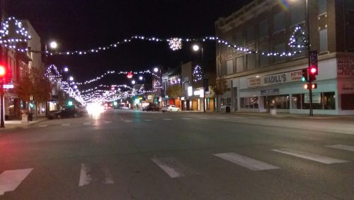 A quiet street at night adorned with festive lights and decorations, creating a warm, inviting atmosphere.
