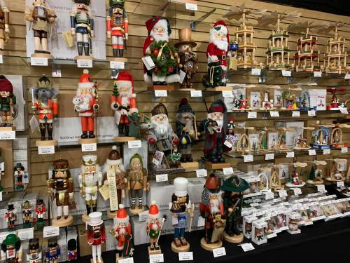 A display of various nutcracker figurines and holiday decorations on shelves, showcasing festive designs and colors.