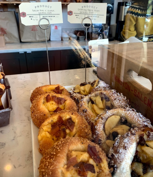 A display of pastries, including bacon and cheese danishes, and apple-filled pastries, with price tags visible.