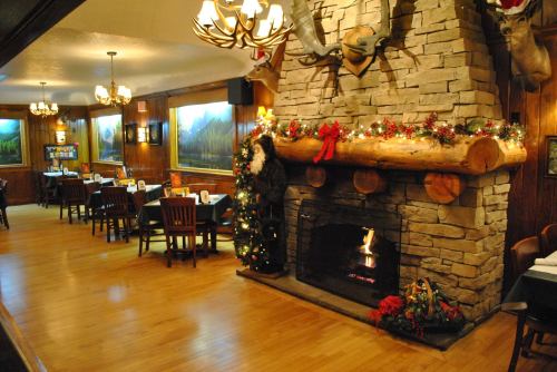 Cozy restaurant interior with a stone fireplace, festive decorations, and wooden tables in a warm, inviting atmosphere.