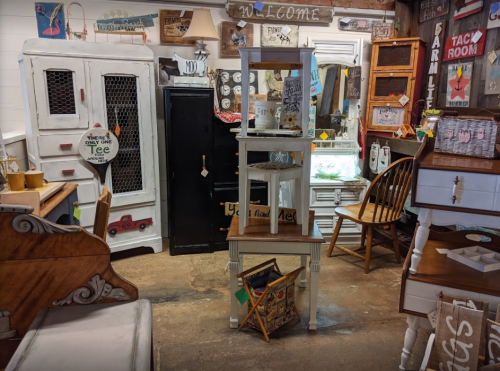 A cozy vintage shop filled with furniture, decor, and signs, creating a warm and inviting atmosphere.