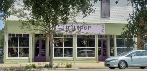 A green storefront with purple doors and windows, featuring the name "Ginger" above, surrounded by trees.