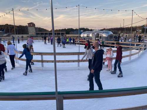 A busy outdoor ice skating rink with people skating and enjoying the winter atmosphere.