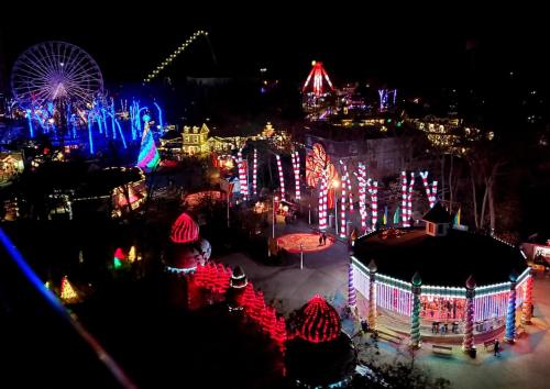 A vibrant amusement park illuminated with colorful lights, featuring a carousel, a Ferris wheel, and festive decorations.
