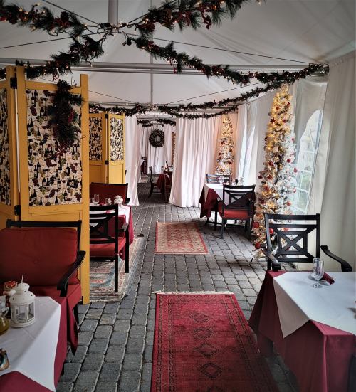 Cozy restaurant interior decorated for the holidays, featuring festive garlands and tables set for dining.