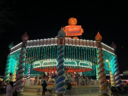 A brightly lit carousel at night, adorned with colorful lights and festive decorations.