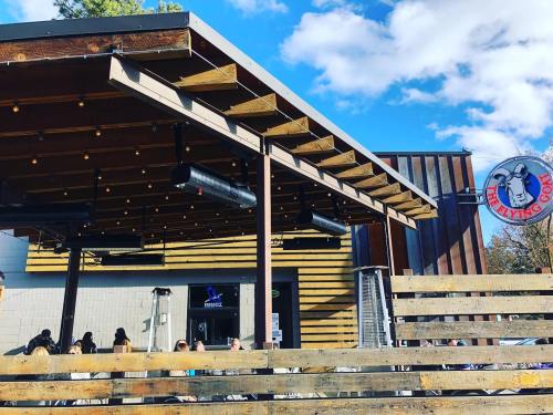 Exterior of The Flying Goat restaurant with wooden beams, outdoor seating, and a blue sky with clouds.