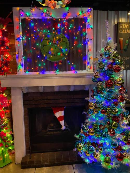 A festive scene featuring a decorated Christmas tree and a fireplace adorned with colorful lights and ornaments.