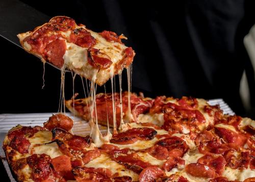 A slice of pepperoni pizza being lifted, showcasing melted cheese and crispy crust.