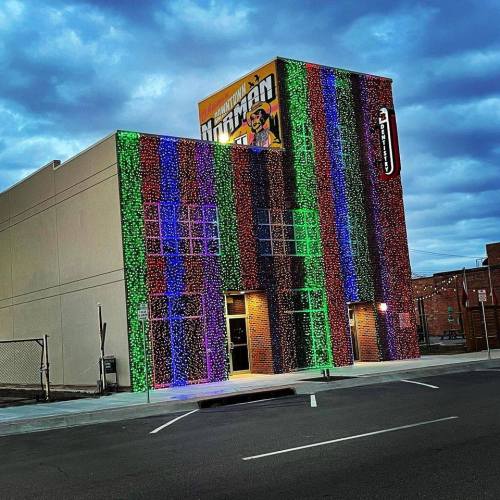 A colorful building adorned with vibrant lights against a cloudy sky, creating a festive atmosphere.