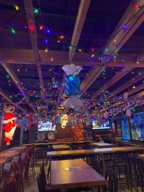 A cozy restaurant interior decorated with colorful lights and festive ornaments, featuring wooden tables and chairs.