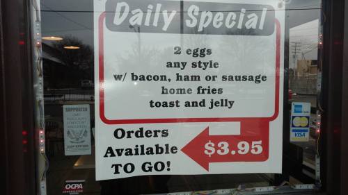 Sign advertising a daily special: 2 eggs with bacon, ham, or sausage, home fries, toast, and jelly for $3.95. To-go orders available.