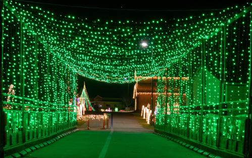A bridge adorned with vibrant green lights, creating a festive atmosphere at night.
