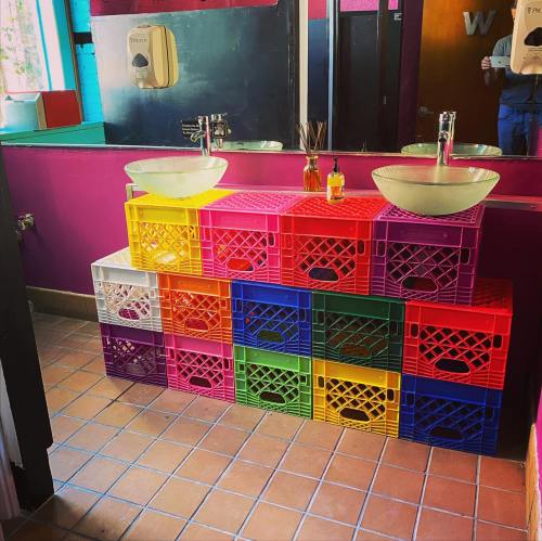 Colorful plastic crates stacked to create a unique sink stand in a vibrant bathroom setting.