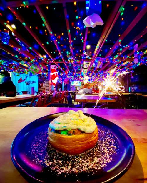 A festive restaurant scene with colorful lights and a sparkler atop a dessert on a plate.