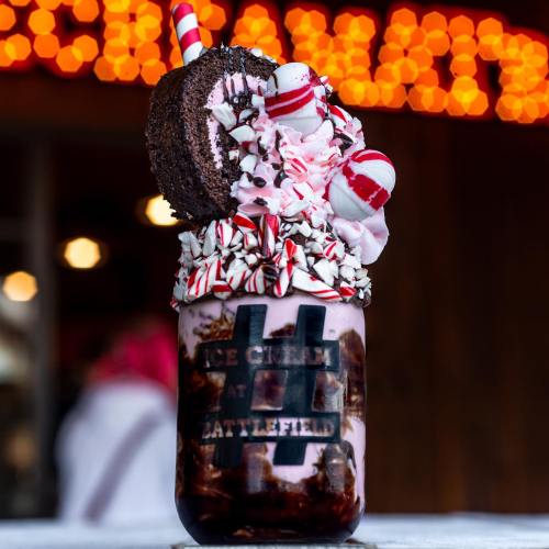 A decadent ice cream sundae in a jar, topped with whipped cream, cookies, and festive candy canes.