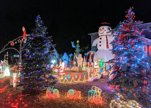 A festive display of colorful Christmas lights, featuring a large snowman, trees, and various holiday decorations.