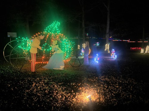 Colorful holiday lights depict a couple in a romantic pose, surrounded by festive decorations in a nighttime setting.