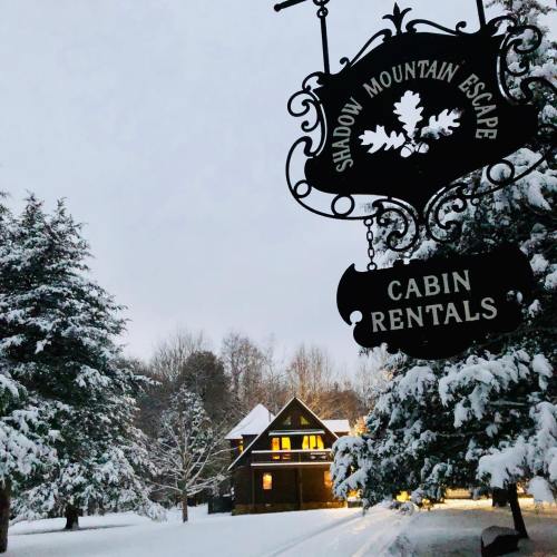 A snowy scene featuring a cabin rental sign and a cozy cabin surrounded by snow-covered trees.