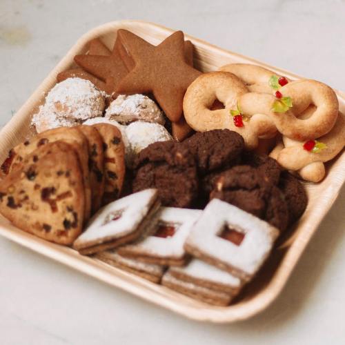 A wooden tray filled with various festive cookies, including gingerbread, star shapes, and chocolate treats.