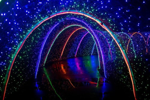 A vibrant tunnel of colorful lights in blue, green, and red, reflecting on a wet surface.