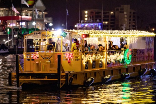 A brightly lit party boat with festive decorations and people enjoying a night on the water.