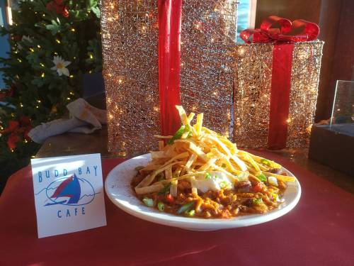 A plate of chili topped with crispy tortilla strips, served at Budd Bay Cafe, with festive holiday decorations in the background.