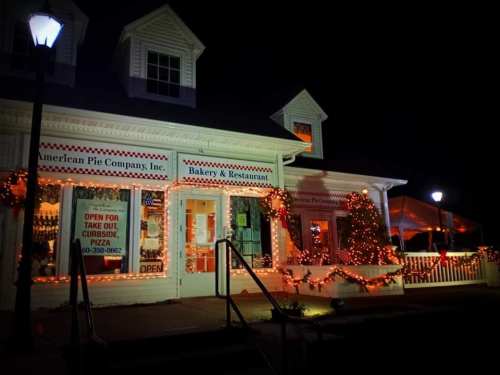 A cozy bakery and restaurant decorated with festive lights at night, featuring a welcoming "Open" sign.