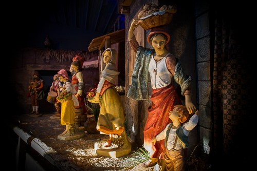 A detailed nativity scene featuring figurines of people in traditional attire, set in a rustic environment.