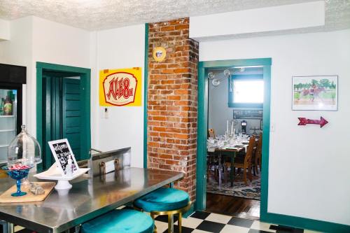 A bright kitchen with a brick column, teal accents, and a dining area visible in the background.