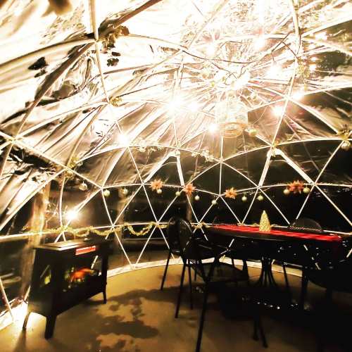 A cozy, illuminated dome interior with a dining table, chairs, and decorative elements, creating a warm atmosphere.