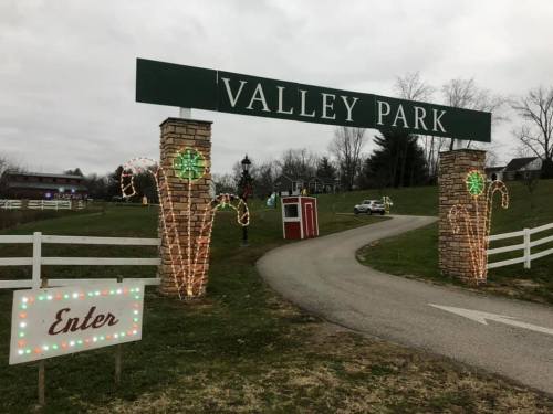 Entrance to Valley Park, featuring festive lights and a sign that says "Enter," with a winding road ahead.
