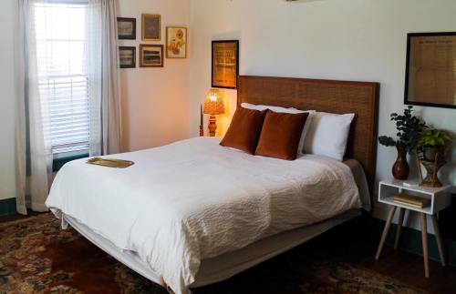 Cozy bedroom with a white bed, brown pillows, a lamp, and framed art on the walls, featuring a warm, inviting atmosphere.