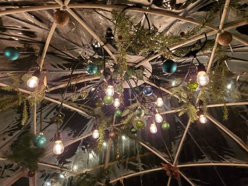 A close-up of a decorated dome ceiling with string lights, ornaments, and greenery.