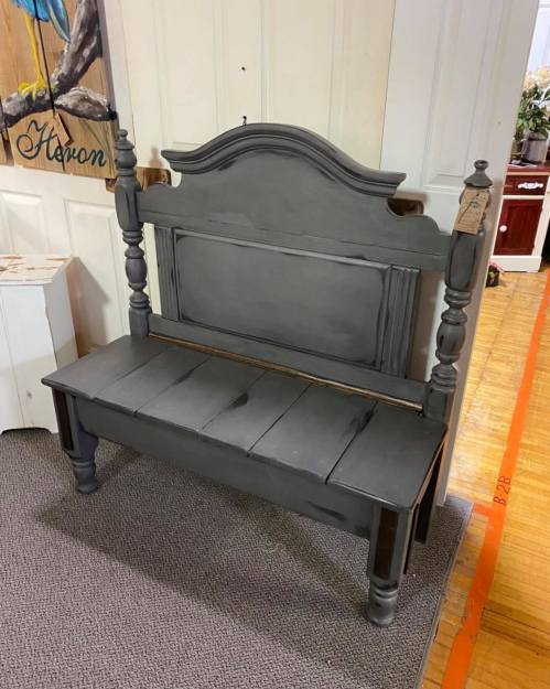 A vintage gray wooden bench with a high back and decorative spindles, placed in a room with light-colored walls.