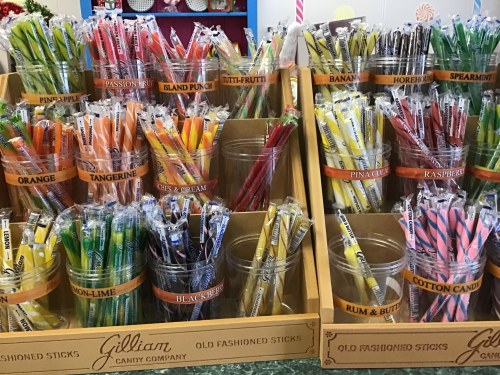 Colorful candy sticks in various flavors displayed in clear containers at Gilliam Candy Company.
