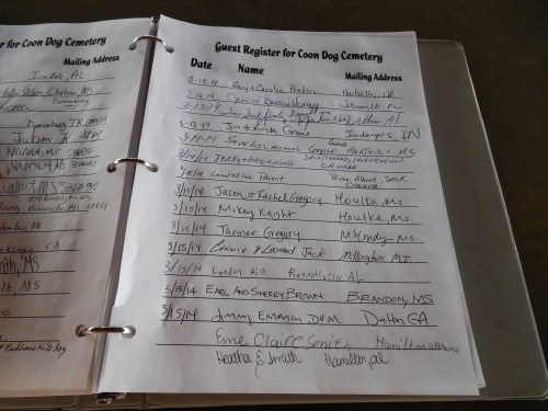 A close-up of a guest register for Coon Dog Cemetery, listing names and mailing addresses with dates.