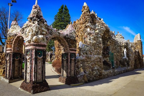 A whimsical stone structure adorned with shells and colorful decorations under a clear blue sky.