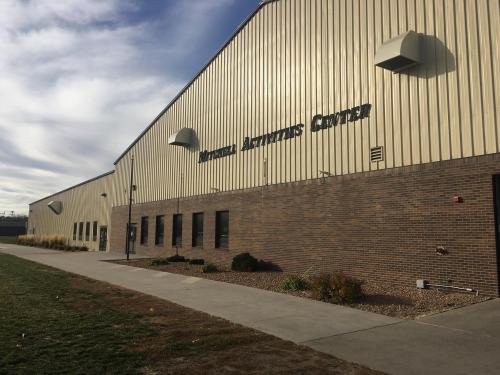 Exterior view of the Mitchell Activities Center, featuring a large metal building with a brick base and grassy area.