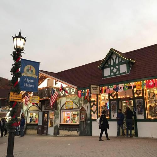 A charming alpine-style building in Helen, Georgia, adorned with festive lights and flags, with people walking around.