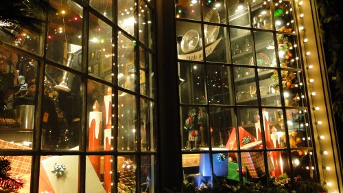 A festive window display adorned with colorful lights, candles, and holiday decorations.