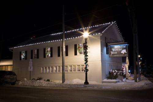 A charming inn decorated with holiday lights and wreaths, set against a snowy night backdrop.