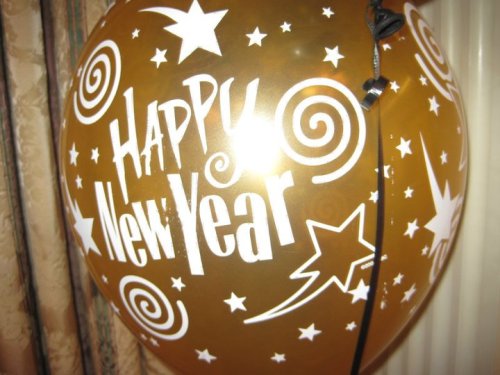 A gold balloon with "Happy New Year" text and decorative stars and swirls.