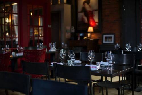 Elegant restaurant interior with empty tables set for dining, featuring wine glasses and a warm ambiance.