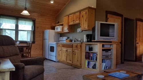 Cozy cabin interior featuring a kitchen with wooden cabinets, a dining area, and a comfortable seating area.