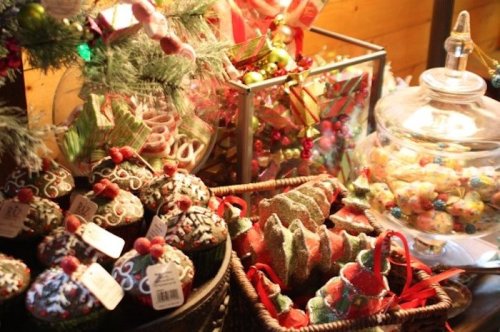A festive display of decorated cupcakes, Christmas trees, and colorful candies in a cozy setting.